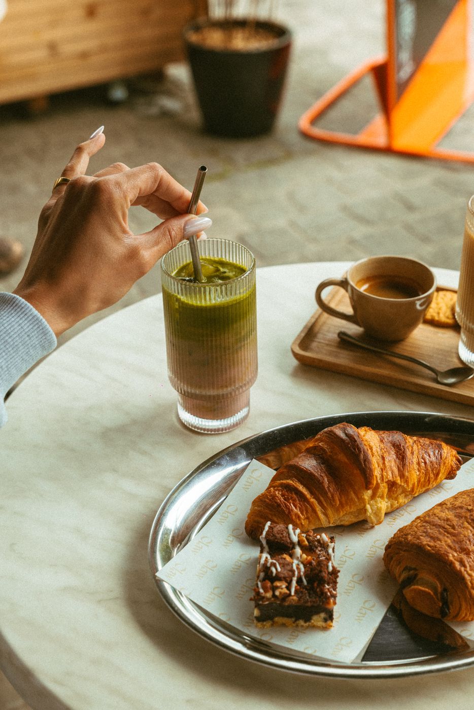 A pink matcha latte next to croissants on the terrace